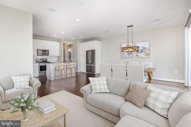 living room with dark wood finished floors, a notable chandelier, recessed lighting, and baseboards