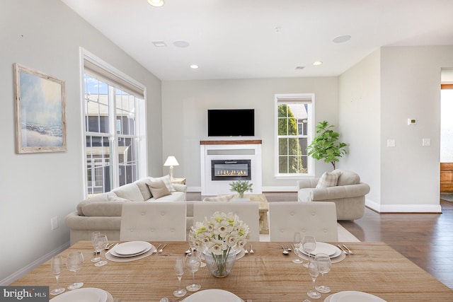 dining room with a glass covered fireplace, recessed lighting, wood finished floors, and baseboards