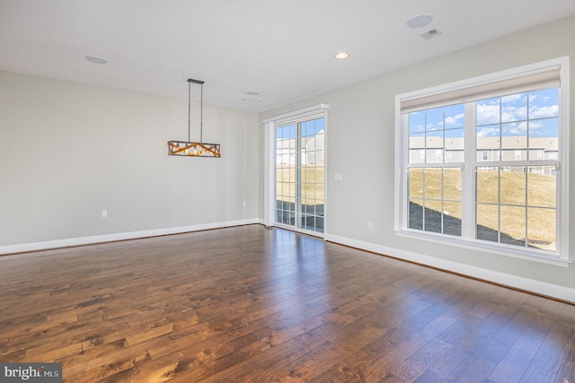 unfurnished dining area featuring dark wood-type flooring, baseboards, and visible vents