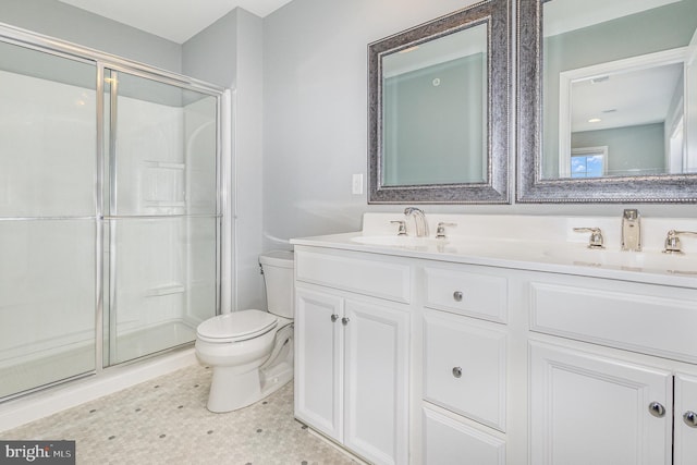 bathroom with double vanity, a stall shower, toilet, and a sink