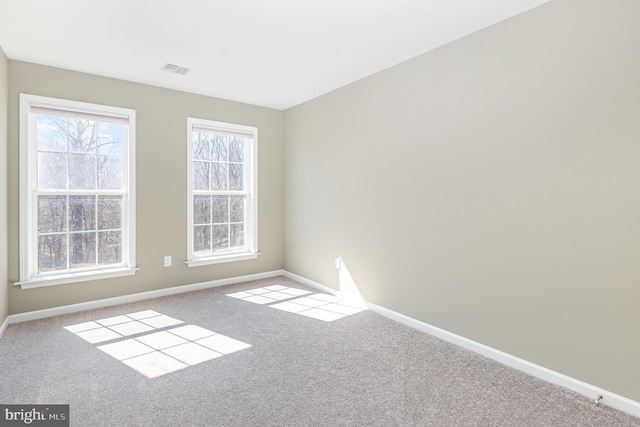 carpeted spare room featuring visible vents and baseboards