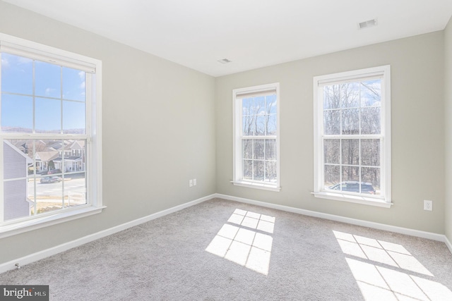 spare room with visible vents, carpet, and baseboards