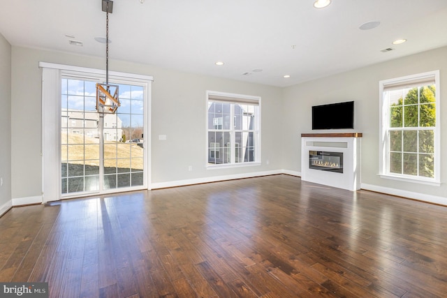 unfurnished living room with dark wood finished floors, a glass covered fireplace, and recessed lighting