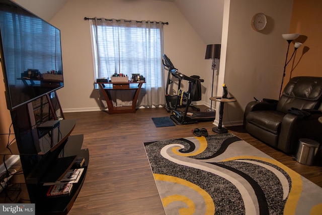 living area with vaulted ceiling, baseboards, and wood finished floors