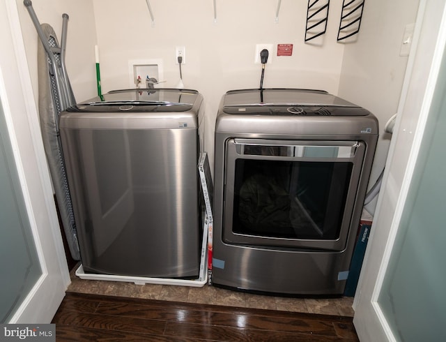 clothes washing area featuring laundry area, washing machine and clothes dryer, and wood finished floors