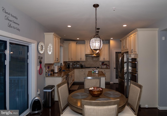 kitchen with decorative backsplash, dishwashing machine, a kitchen island, freestanding refrigerator, and hanging light fixtures