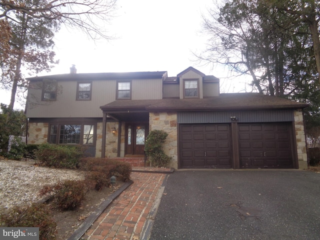 view of front of house featuring a garage, stone siding, and driveway