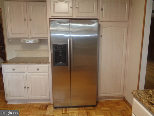 kitchen featuring stone counters and stainless steel fridge with ice dispenser