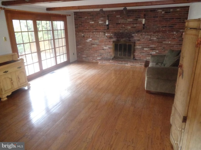 unfurnished living room featuring brick wall, a fireplace, and wood finished floors