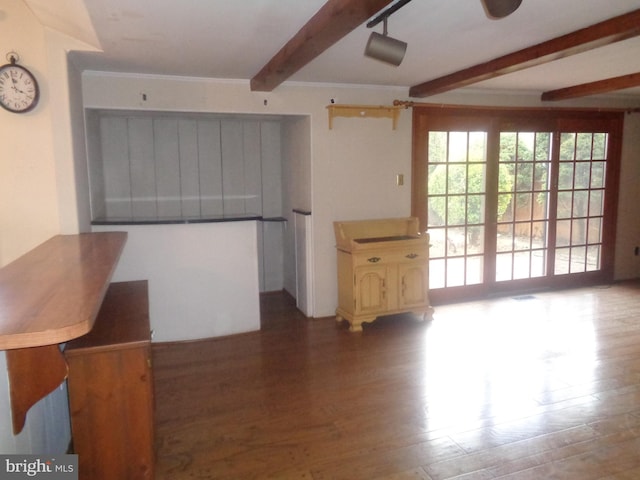 interior space with wood finished floors, beam ceiling, and crown molding