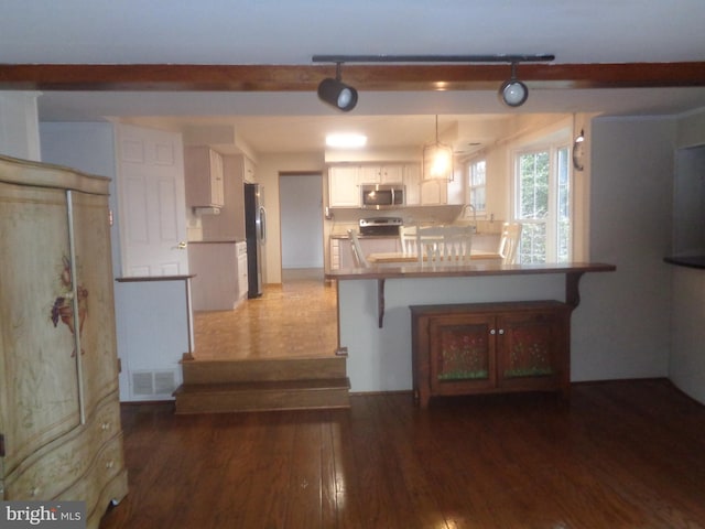 kitchen featuring a peninsula, wood finished floors, visible vents, white cabinets, and appliances with stainless steel finishes