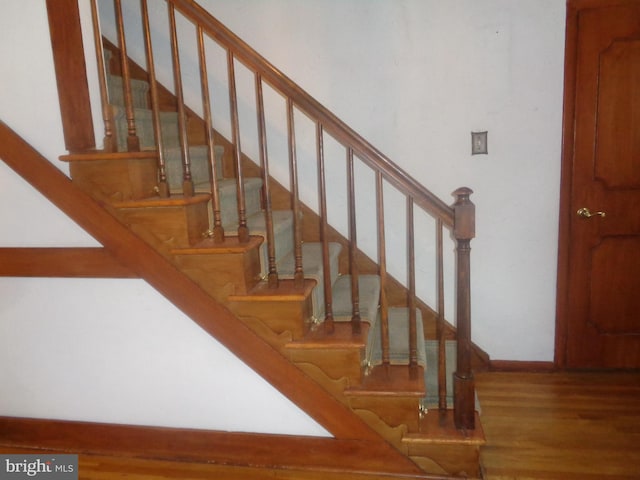 staircase featuring baseboards and wood finished floors