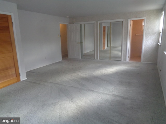 unfurnished bedroom featuring carpet floors and two closets