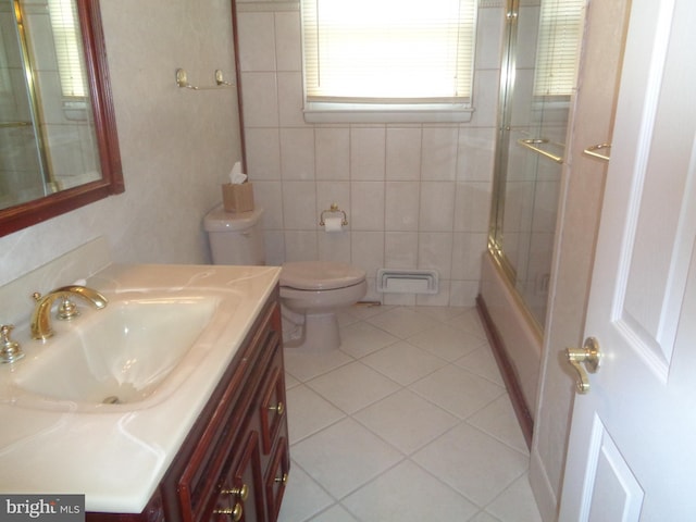 bathroom featuring enclosed tub / shower combo, tile patterned flooring, toilet, tile walls, and vanity