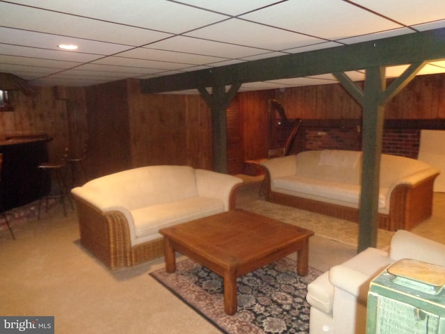 interior space featuring light carpet, wood walls, and a drop ceiling