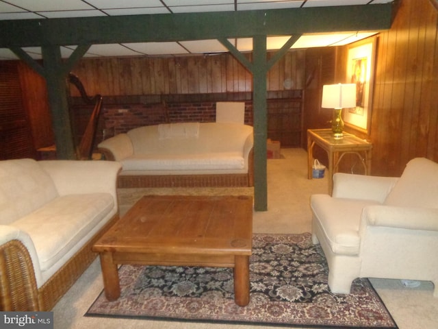 carpeted living area with a paneled ceiling and wood walls