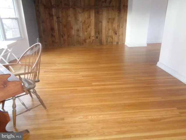 dining area featuring wooden walls, light wood-style flooring, and baseboards