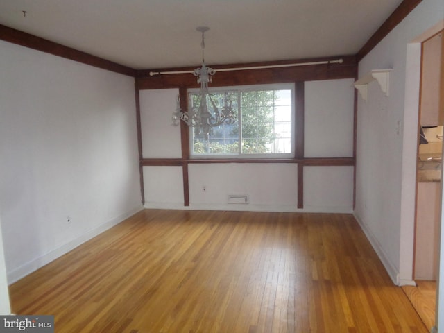 unfurnished dining area with a notable chandelier, light wood-style flooring, and baseboards