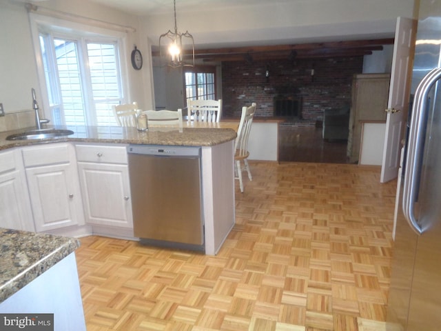 kitchen featuring a sink, white cabinets, appliances with stainless steel finishes, light stone countertops, and pendant lighting