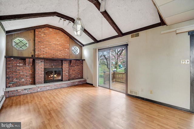 unfurnished living room featuring visible vents, wood finished floors, beam ceiling, and a brick fireplace