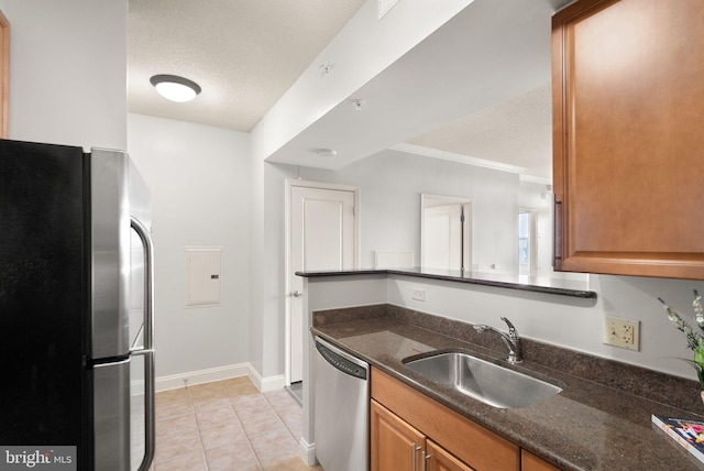 kitchen featuring a textured ceiling, appliances with stainless steel finishes, dark stone counters, and a sink