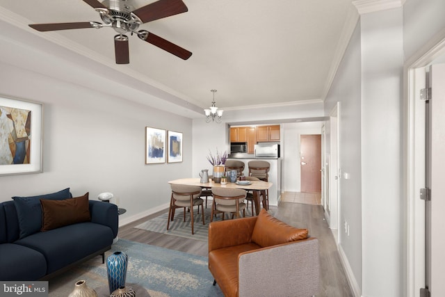 living area featuring light wood-style floors, baseboards, a chandelier, and crown molding