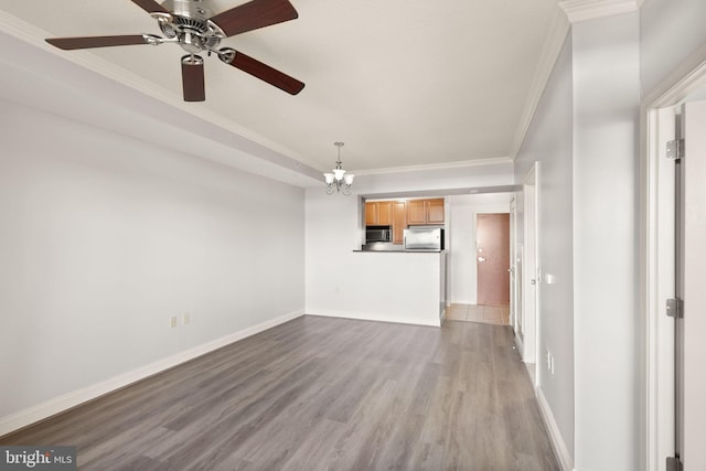unfurnished living room with a notable chandelier, crown molding, baseboards, and wood finished floors