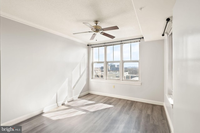 spare room featuring a textured ceiling, ceiling fan, wood finished floors, and baseboards