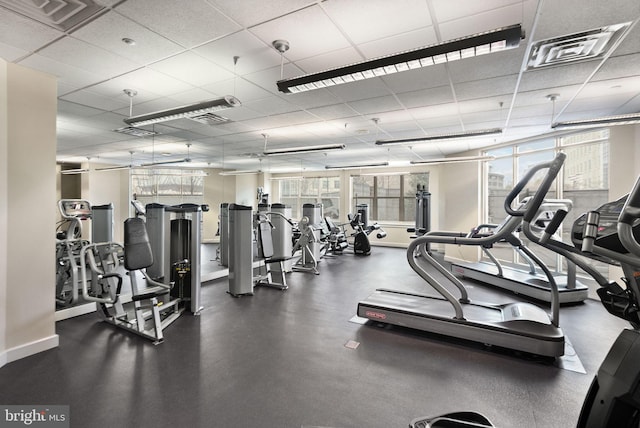 exercise room featuring a paneled ceiling, visible vents, and baseboards