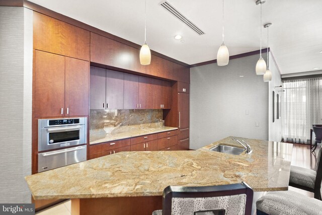 kitchen with oven, a breakfast bar, a sink, visible vents, and a warming drawer