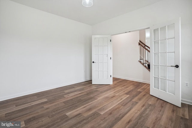 empty room with stairs, baseboards, and wood finished floors