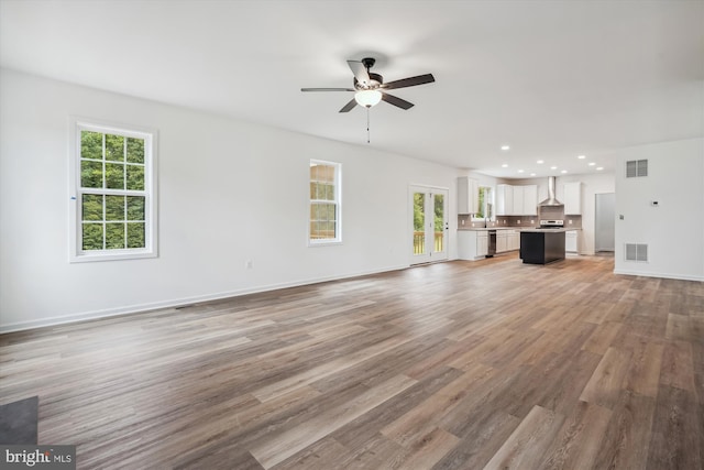 unfurnished living room featuring a healthy amount of sunlight, visible vents, and light wood finished floors