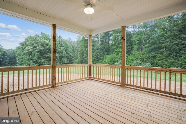 wooden deck featuring a wooded view and a ceiling fan