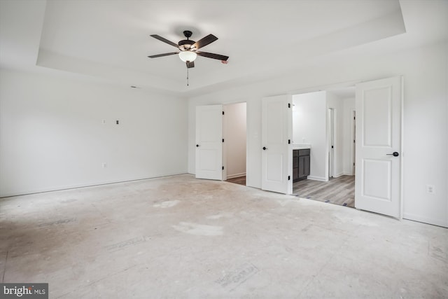 unfurnished bedroom featuring ensuite bathroom and a tray ceiling