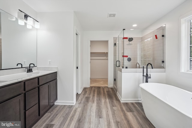 full bath featuring visible vents, wood finished floors, vanity, a freestanding tub, and a shower stall