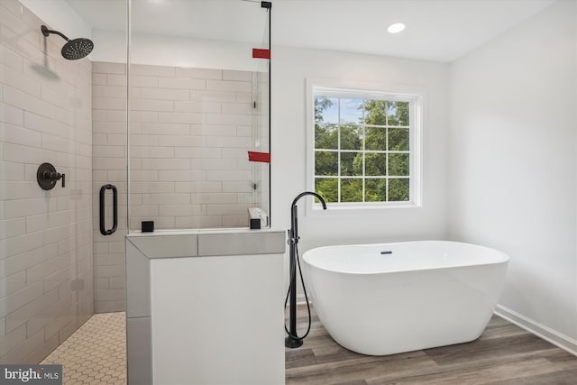 bathroom featuring a stall shower, baseboards, wood finished floors, a freestanding tub, and recessed lighting