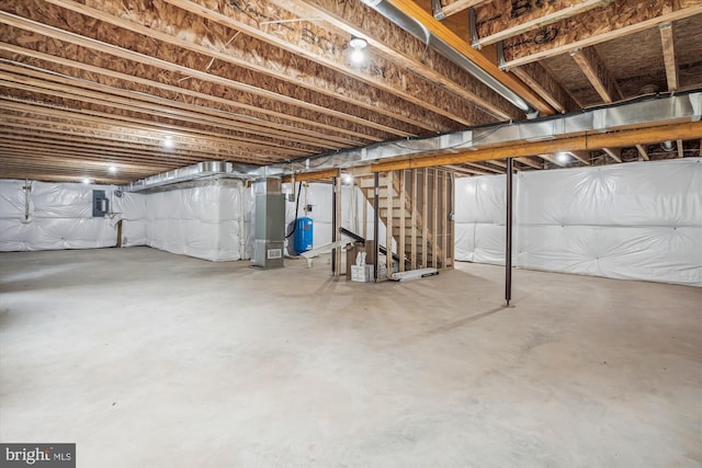 unfinished basement featuring electric panel and heating unit