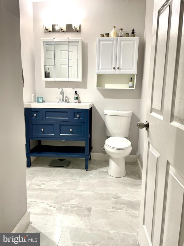 bathroom with baseboards, vanity, and toilet