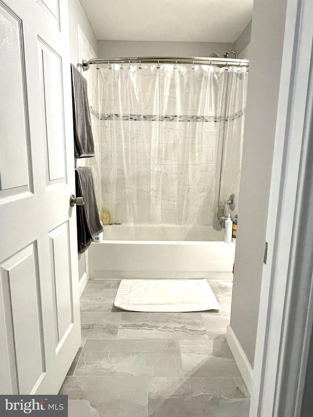 full bathroom with marble finish floor and shower / bath combination with curtain