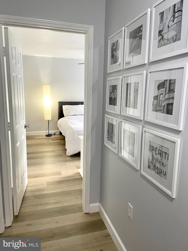 hallway featuring light wood-style flooring and baseboards