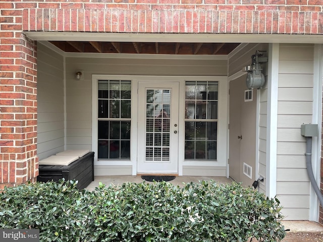 property entrance featuring brick siding and visible vents