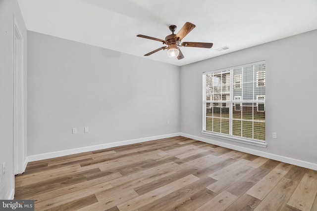 empty room with a ceiling fan, baseboards, visible vents, and wood finished floors