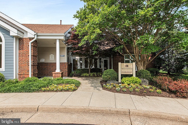 exterior space with brick siding and a shingled roof