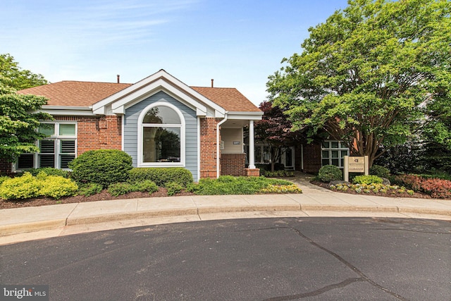 view of front of home with a shingled roof and brick siding