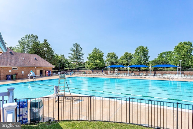 community pool with a patio area and fence