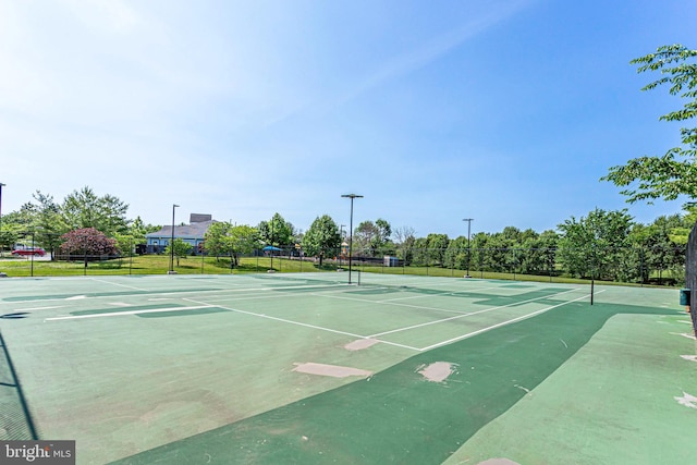 exterior space with a tennis court and fence