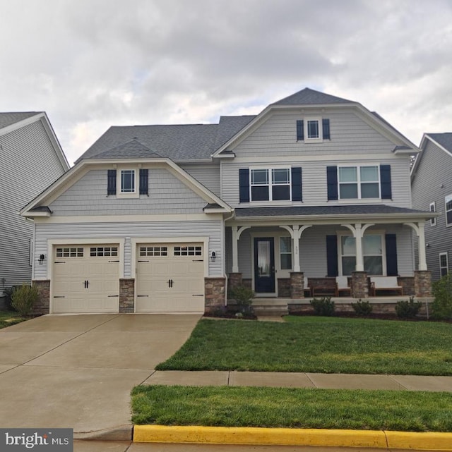 view of front of property featuring stone siding, a porch, driveway, and a front lawn