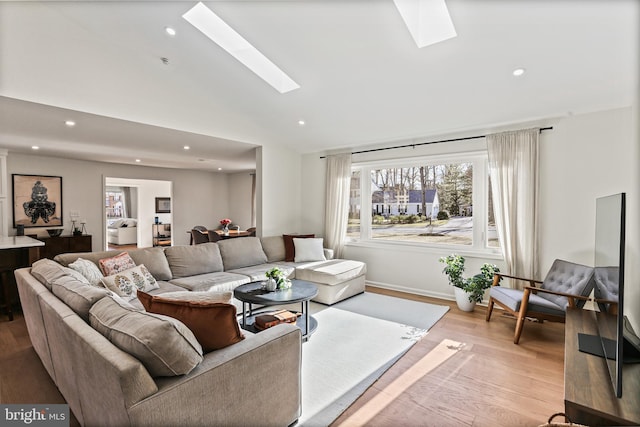 living room with baseboards, vaulted ceiling with skylight, wood finished floors, and recessed lighting