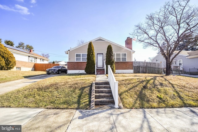 view of front of property featuring concrete driveway, a chimney, fence, a front lawn, and brick siding