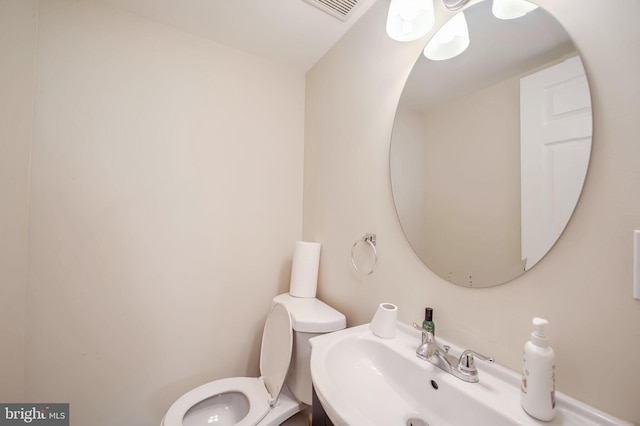 half bath featuring toilet, visible vents, and a sink